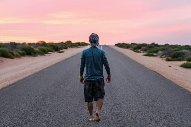 Man walking alone on the road at sunset